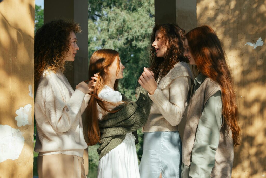 Four young women stand together in a park, bonding in the summer sunlight.