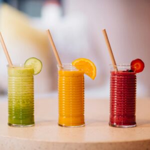 Three vibrant fruit smoothies with bamboo straws, perfect for a refreshing summer drink.