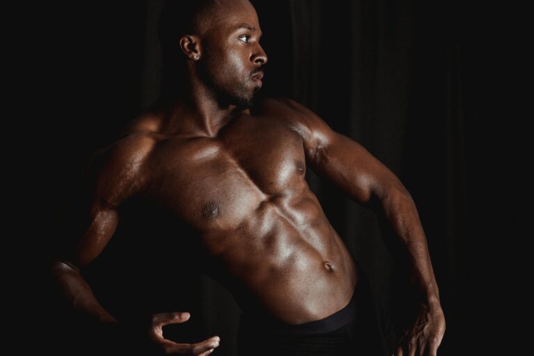 A powerful pose showcasing strength and muscular definition against a dark backdrop.
